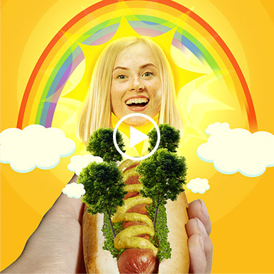 Surreal image of a hot dog decorated with trees, held by a hand, with a smiling blonde woman as the sun, rainbow, and clouds in the background